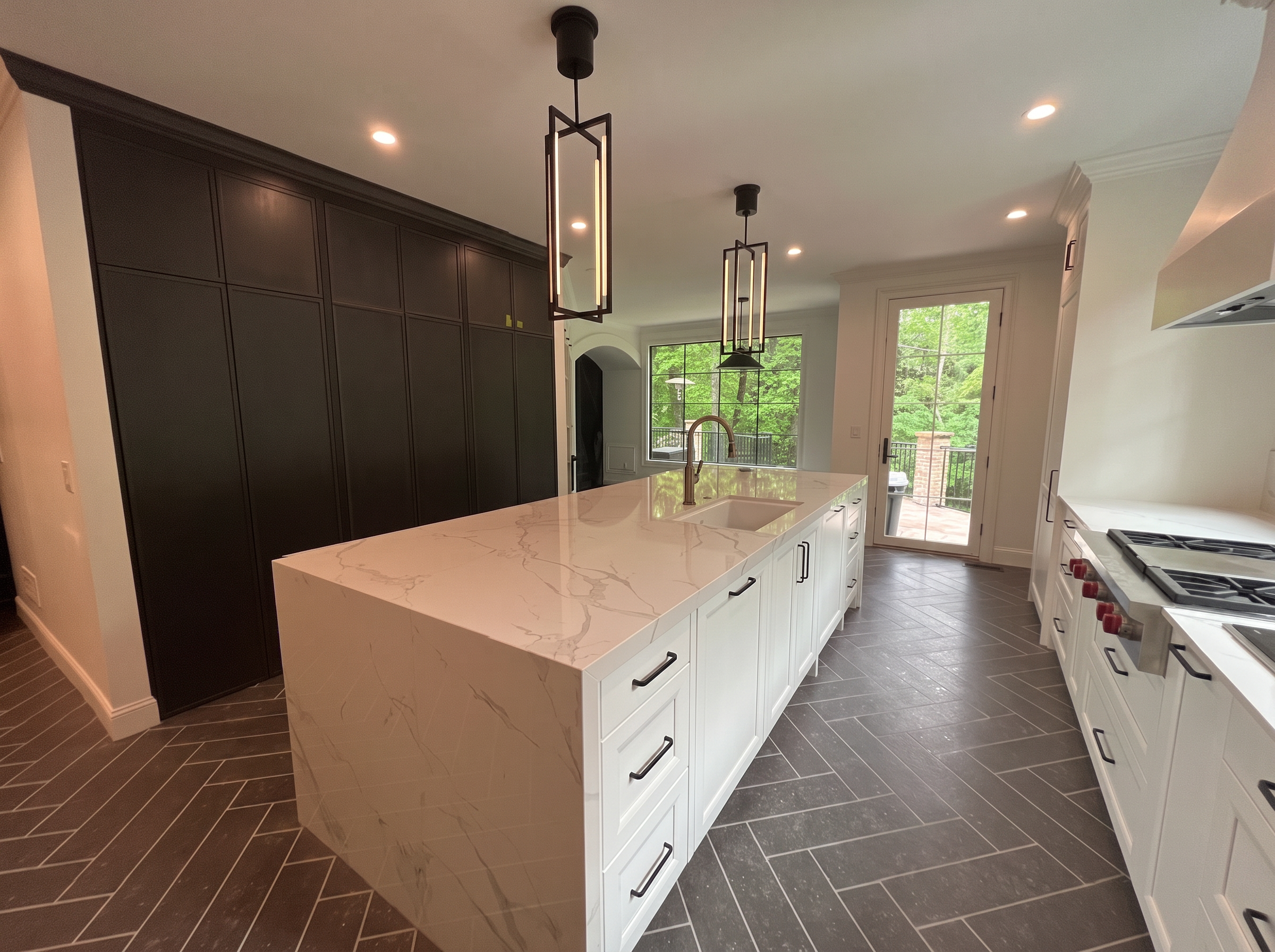 Kitchen with dark paneled pantry wall and pale stone island