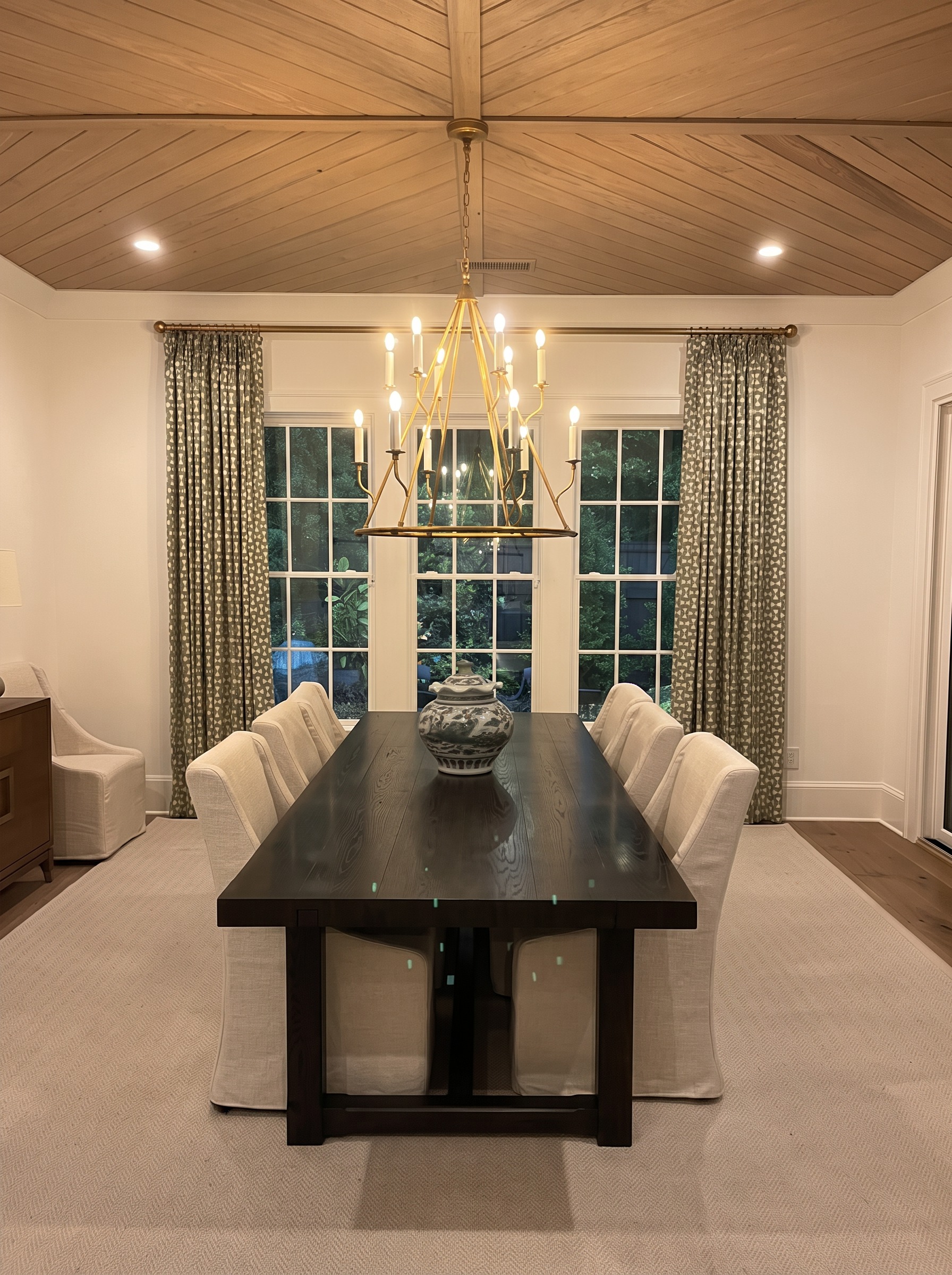 Dining room with wood ceiling, brass chandelier, and slipcovered chairs